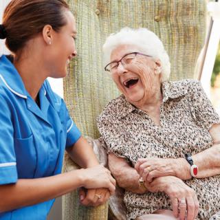 A caregiver shares a joyful moment with an elderly woman.