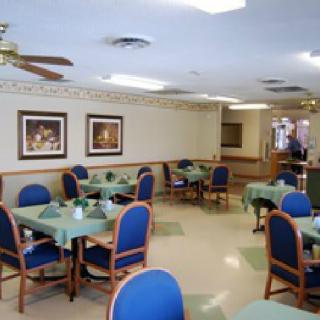 An empty dining area with tables and chairs arranged neatly, featuring decorated walls and bright lighting.