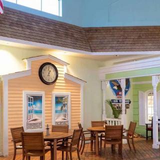 A cozy indoor dining area with tables and chairs, featuring decorative walls and a clock.