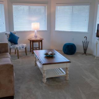 A cozy living room with a sofa, wooden coffee table, and bright lighting.