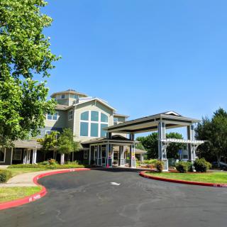 A modern building with a driveway and surrounding greenery.