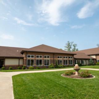 A residential building with a well-maintained lawn and driveway under a clear blue sky.