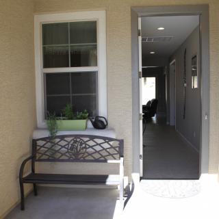A bench is placed near a window with a planter on top, beside an open door leading to a hallway.