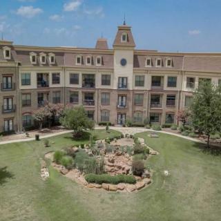 A large residential building with a clock tower and a landscaped garden in front.