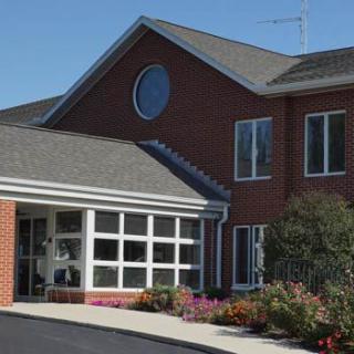 A brick building with tall windows and a landscaped entrance.