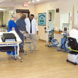 A team of medical professionals assists a patient during a physical therapy session in a rehabilitation clinic.