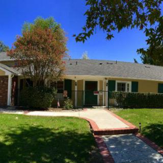 A charming suburban house with a well-kept lawn and clear blue sky.