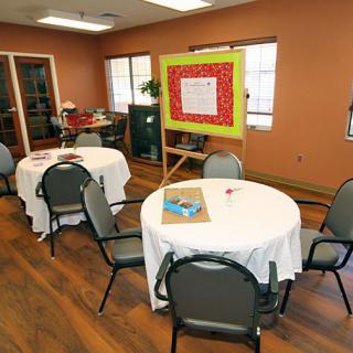 A meeting room with tables covered in white tablecloths, surrounded by chairs, and a presentation board on an easel.