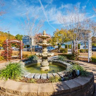 A serene fountain surrounded by autumn foliage and a clear blue sky.