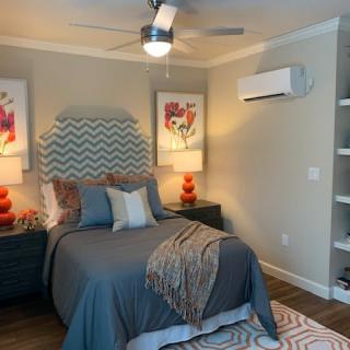 A modern bedroom with a stylish bed, decorative lamps, and artwork on the walls.