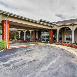 Entrance to a building with an arched driveway and landscaped surroundings.