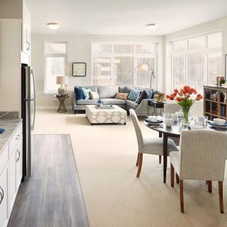 A modern open-concept living space featuring a comfortable seating area, a dining table set for four, and a contemporary kitchen.