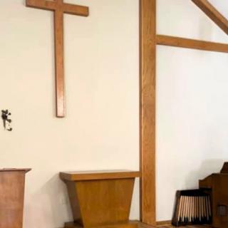 Interior of a church featuring a wooden cross and pulpit.