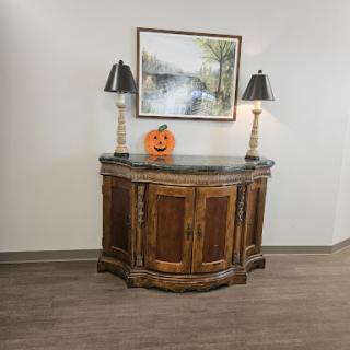 A beautifully styled wooden cabinet adorned with decorative lamps and a festive pumpkin, complemented by an artistic wall piece.