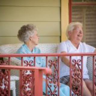 Two elderly individuals enjoying a conversation on a porch.