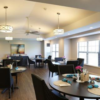A well-lit dining room with neatly arranged tables and chairs, featuring modern decor.