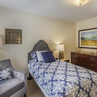 A cozy bedroom featuring a single bed with patterned bedding, complemented by stylish decor and artwork.