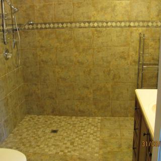 A modern bathroom with tiled walls and a walk-in shower.
