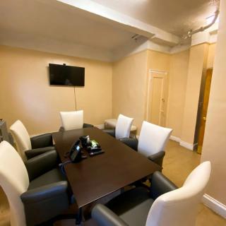 A conference room with a table, chairs, and a wall-mounted TV.