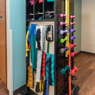 A neatly organized fitness storage rack featuring various exercise tools such as dumbbells and resistance bands.