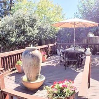 A serene outdoor deck featuring a decorative fountain and dining area, perfect for enjoying sunny days.