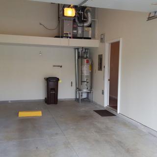 An empty garage with a visible water heater and utility setup.