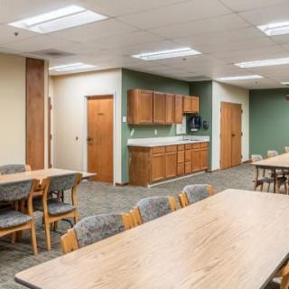 A spacious meeting room with tables, chairs, and a kitchenette.