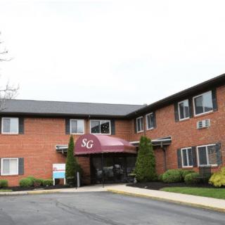 A brick residential building with an entrance featuring a maroon awning labeled '36'.