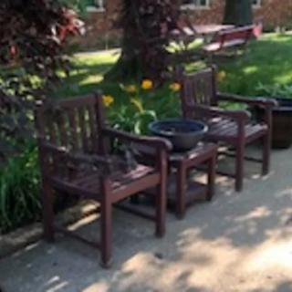 Wooden chairs set in a garden with lush greenery.