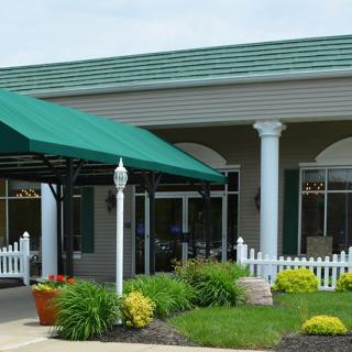 A building entrance with a green awning and neatly landscaped garden.