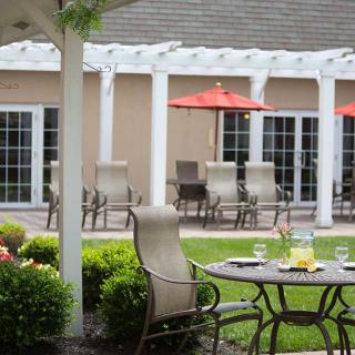 A serene patio setting with outdoor furniture, including a table and chairs, situated in a lush garden.