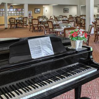 A grand piano in a dining area with tables and chairs.