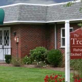 The exterior of a rehabilitation and skilled nursing facility with a sign in front.