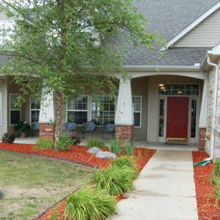A well-maintained front yard with a red mulch pathway leading to a welcoming house entrance.