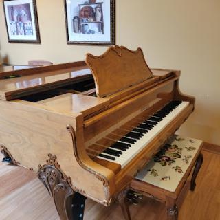 A beautifully crafted wooden grand piano, elegantly placed in a cozy room.