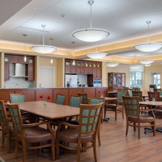 A spacious dining area with wooden tables and chairs, well-lit with modern ceiling lights.