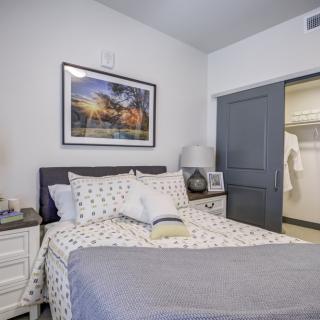 A cozy bedroom with a neatly made bed, closet, and stylish decor.