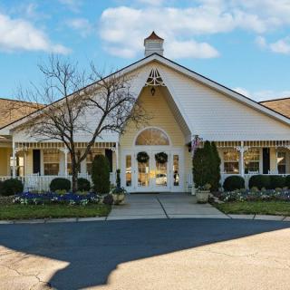 A charming white residential building with a landscaped entrance and clear blue skies.