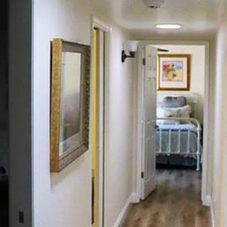 A warmly lit hallway leading to a bedroom, featuring wall decor and wooden flooring.