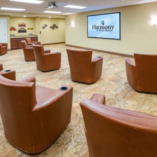 A modern conference room with comfortable leather chairs arranged in rows facing a large screen, suitable for meetings or presentations.