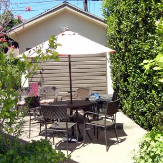 A cozy outdoor patio area with seating and a sunshade, perfect for enjoying the garden.
