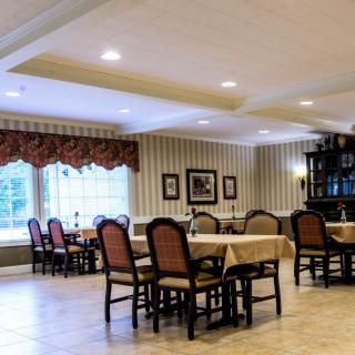 A well-lit dining room with tables and chairs arranged neatly, featuring elegant decor and large windows.