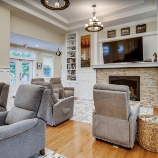 A cozy living room featuring comfortable armchairs, a modern fireplace, and a large television, all set on elegant hardwood flooring.