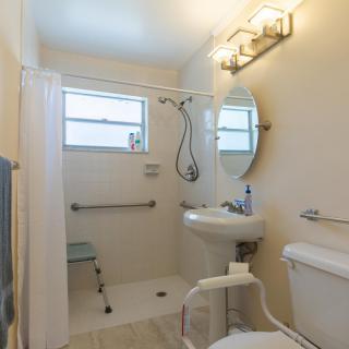 Accessible bathroom with a shower, sink, and toilet equipped with grab bars.