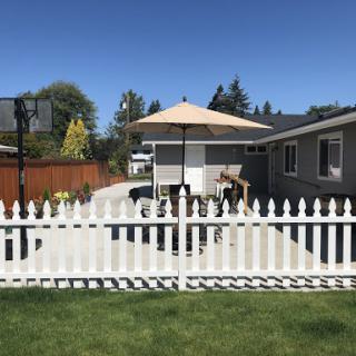 A cozy backyard with a white picket fence and an umbrella on a sunny day.