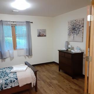 A cozy bedroom with a wooden bed, dresser, and simple decor.