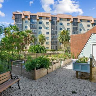 A beautiful view of a modern apartment building surrounded by lush landscaping and garden areas.
