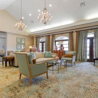 A spacious and elegantly furnished living room with chandeliers, comfortable seating, and large windows.