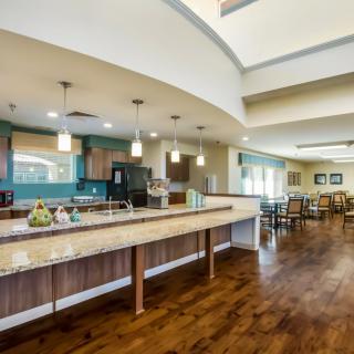 A spacious and modern kitchen with a dining area, featuring wooden floors and contemporary lighting.