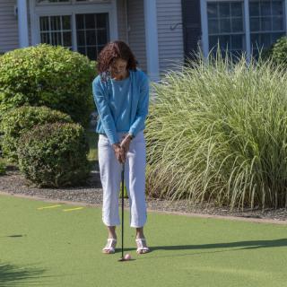 A woman playing golf on a putting green outside during the day.